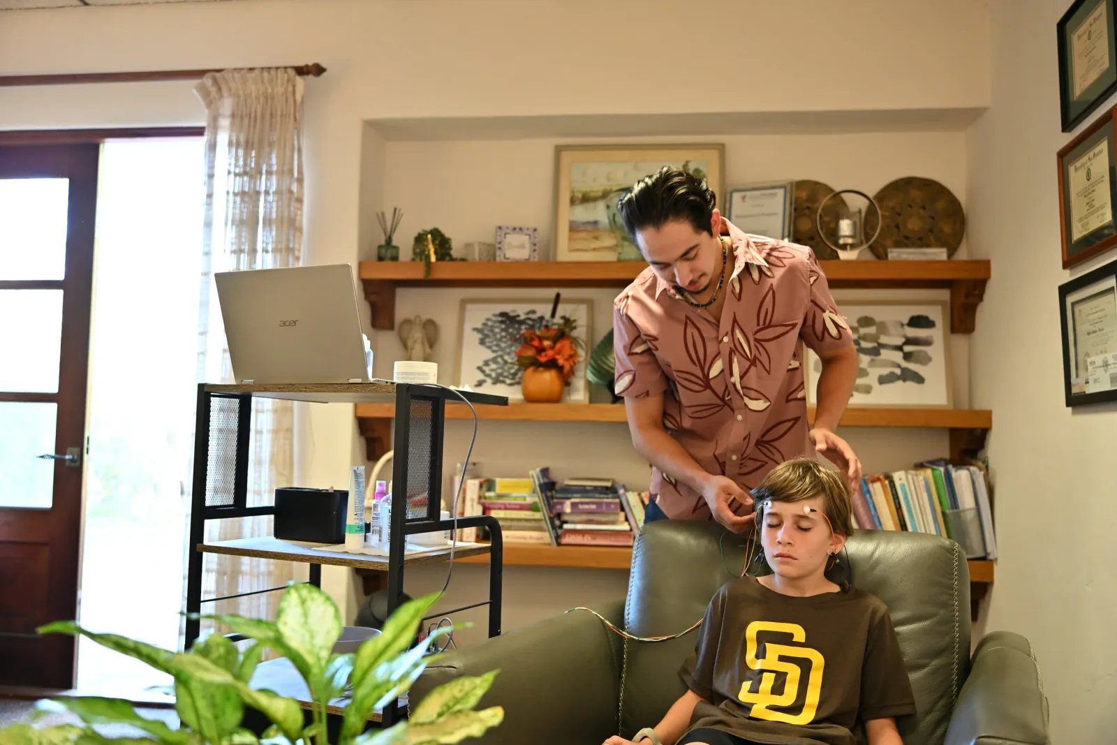 A practitioner placing LENS Neurofeedback sensors on a teenage client at Empowered Purpose